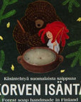 Solan Korven isäntä -saippua suloisessa tummanvihreässä pahvipakkaksessa, jota koristavat piirretyt havut sekä saippuapataa sekoittavat karhu ja punahiuksinen tyttö.