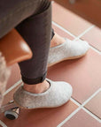 Glerupsin harmaat shoe-malliset ja nahkapohjaiset huopatossut laattalattiaa vasten.