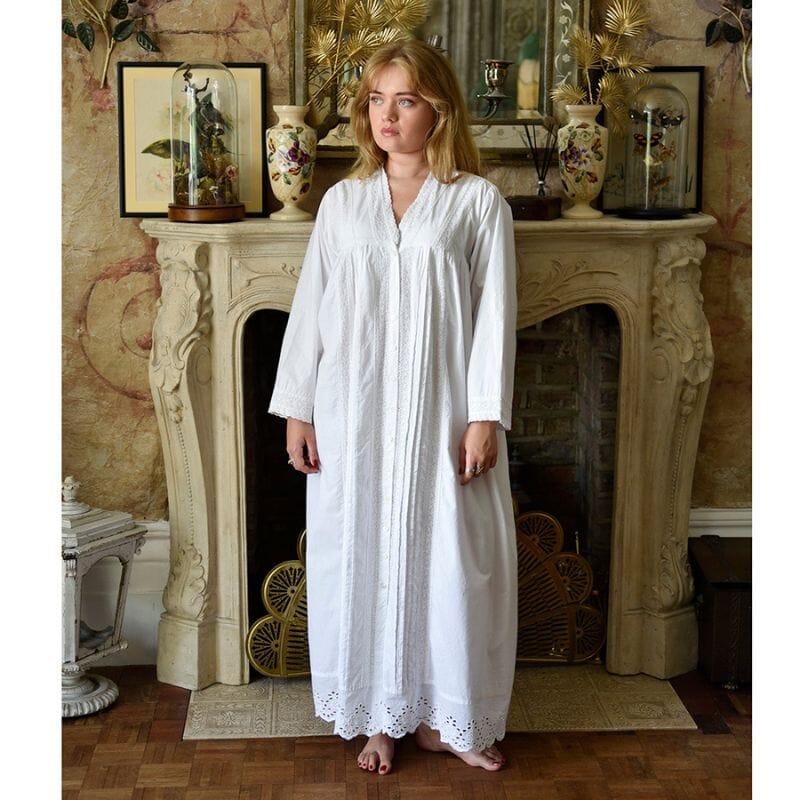 Powell Craftin valkoinen pitkähihainen naisten Claudia-puuvillayöpaita antiikkisen takan edessä seisovan naisen yllä. 