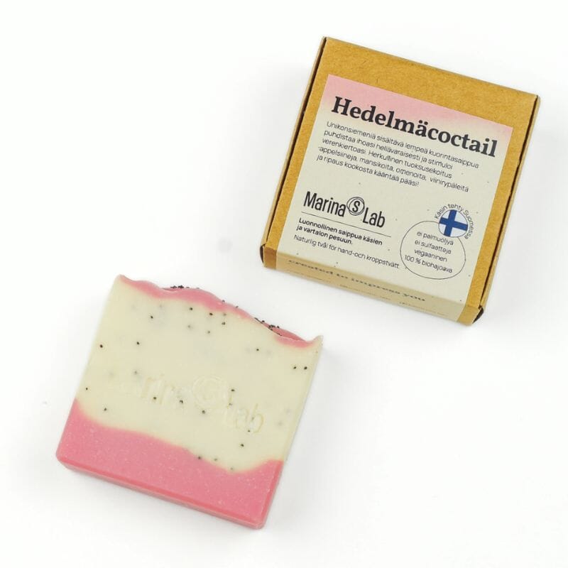 Marina's Labin kuoriva Hedelmäcocktail-palasaippua ja sen kartonkipakkaus valkoisella pohjalla. Saippuassa on väreinä valkoista ja herkullisen vaaleanpunaista ja niiden seassa unikonsiemen-pilkkuja.