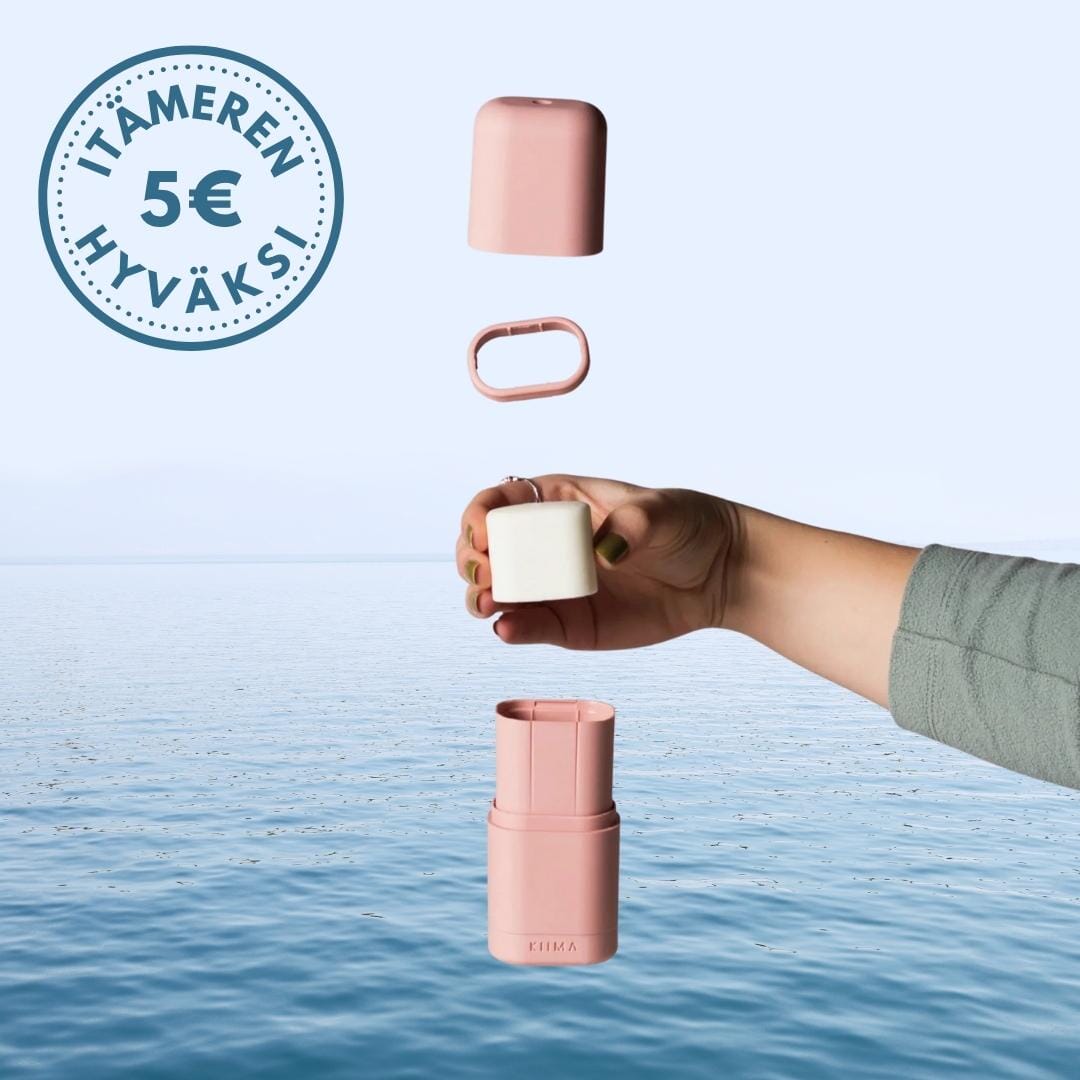 Roosan värinen KIIMA-deodoranttiaplikaattori ja Kaurilan saunan deopala, taustalla sininen meri. Vasemmassa yläkulmassa logo, jossa lukee 
