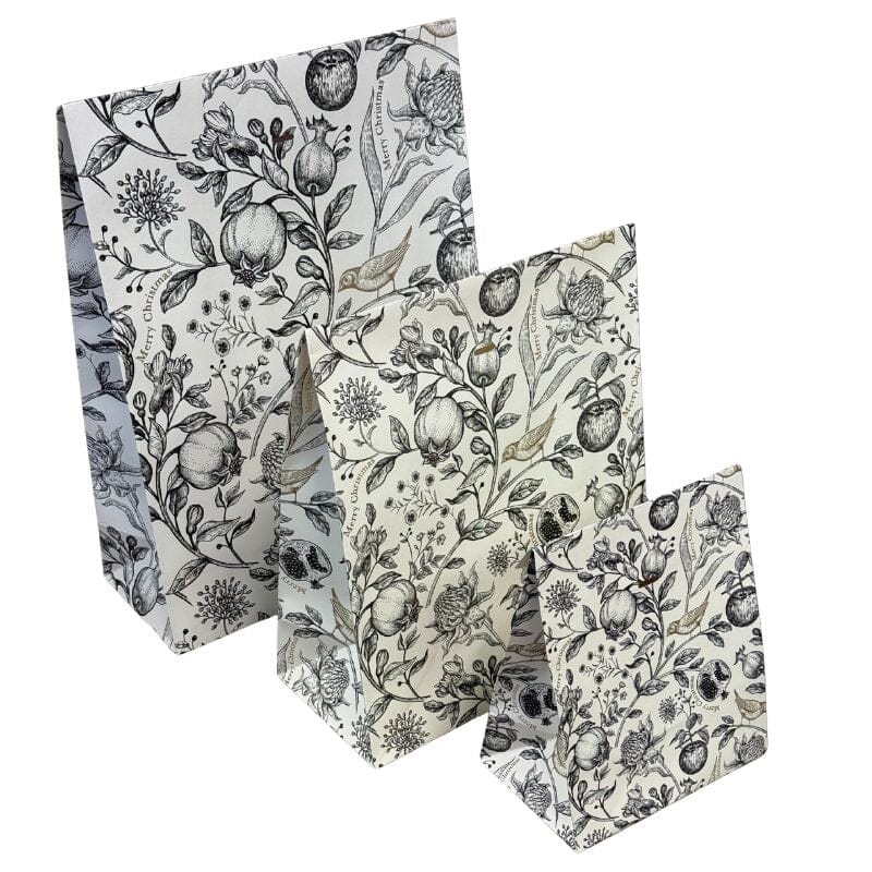 Kolme eri kokoista Kultalintu -lahjapussia sävyssä valkoinen, joissa valkoisella pohjalla mustia kukka- ja hedelmäköynnöksiä, joiden keskellä pieni kultainen lintu. 