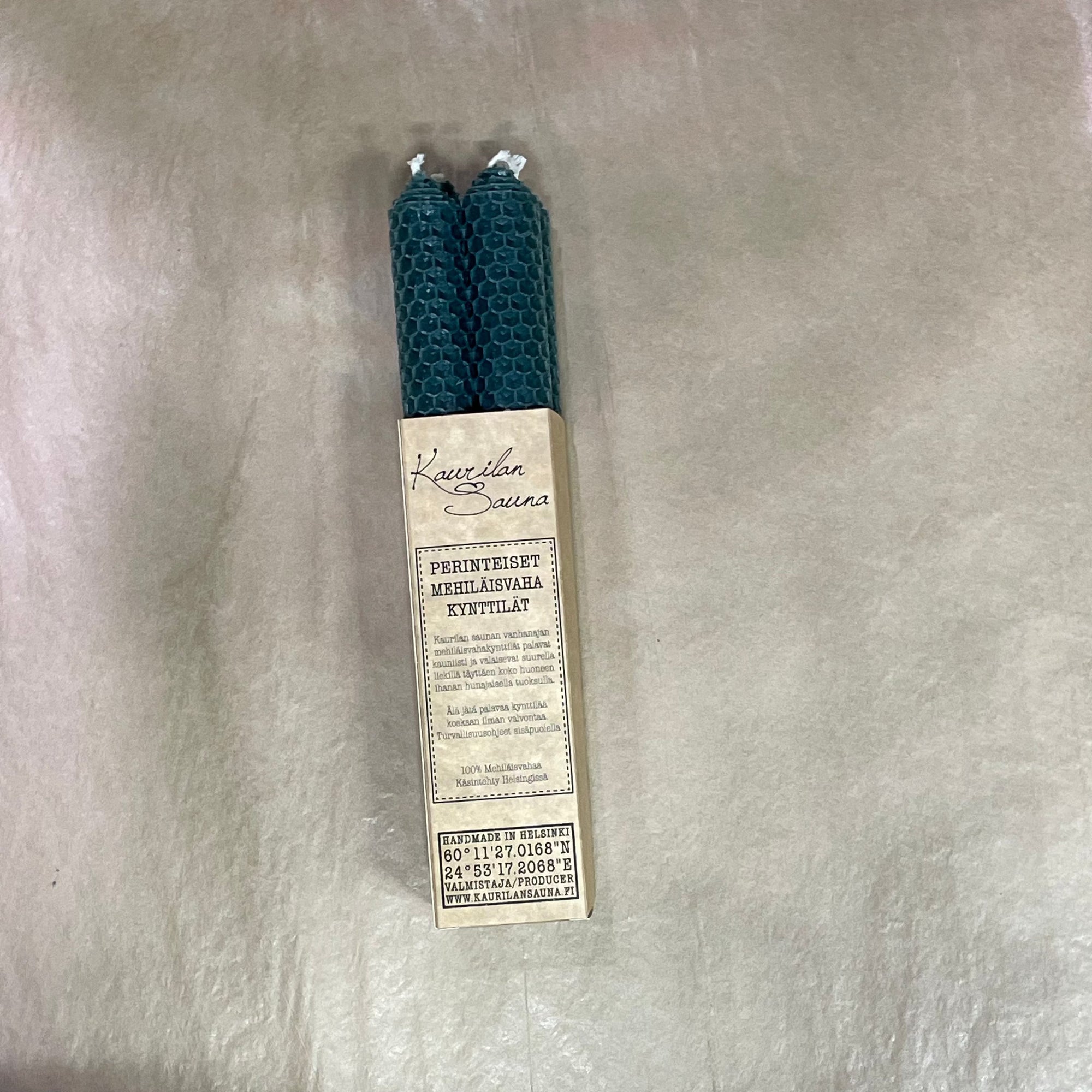 Kaurilan Saunan metsänvihreät mehiläisvahakynttilät 4 kpl pakkauksessa luonnollisen ruskean silkkipaperin päällä.