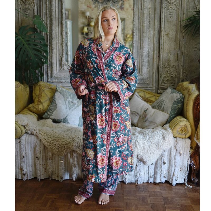 Powell Craftin puuvillapyjama ja -kimono-aamutakki yllä seisova nainen antiikkisen sohvan edessä. 