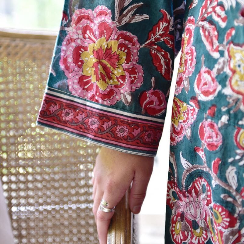 Yksityiskohta Powell Craftin puuvillaisen kimono-aamutakin hihasta, jossa männynvihreällä pohjalla punaisen-, pinkin- ja sinapinsäyisiä kukkakuvioita.