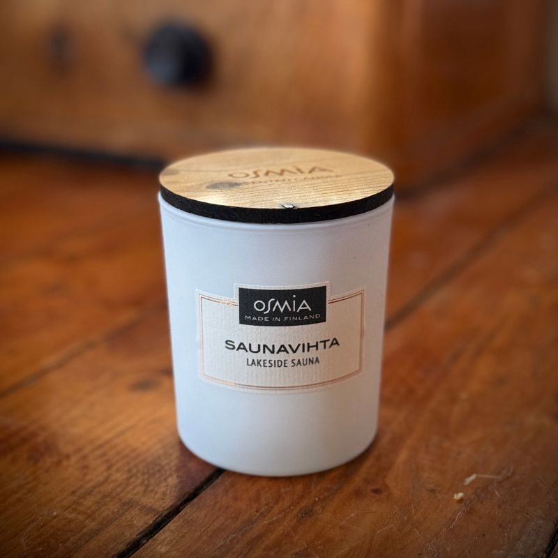 Osmian Saunavihta -tuoksukynttilän valkoinen lasipurkki ja puinen kansi ovat pelkistetyn tyylikkäät ja raikkaat. Kuvatu vanhalla puisella lattialla. 