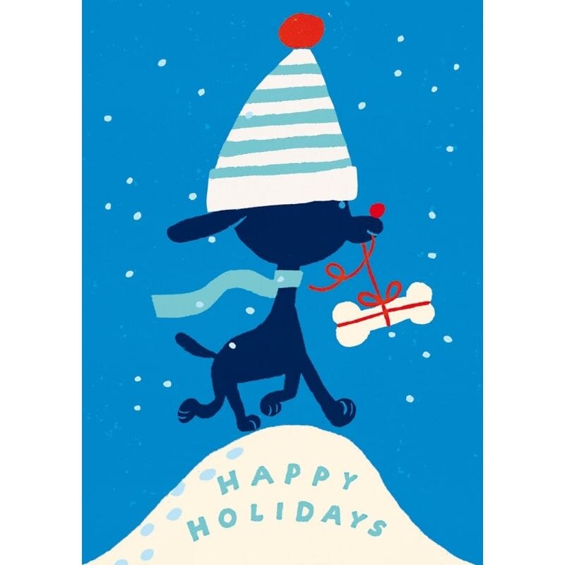 Kehvola Designin Rudolf-postikortissa soma piirretty tummansininen koira kantaa luun mallista pakettia suustaan roikkuvasta punaisesta nauhasta. Päässä koiralla on valkoraitainen ja punatupsuinen pipo. Koiran alla lumikinoksessa lukee mintunvihreällä "Happy Holidays".