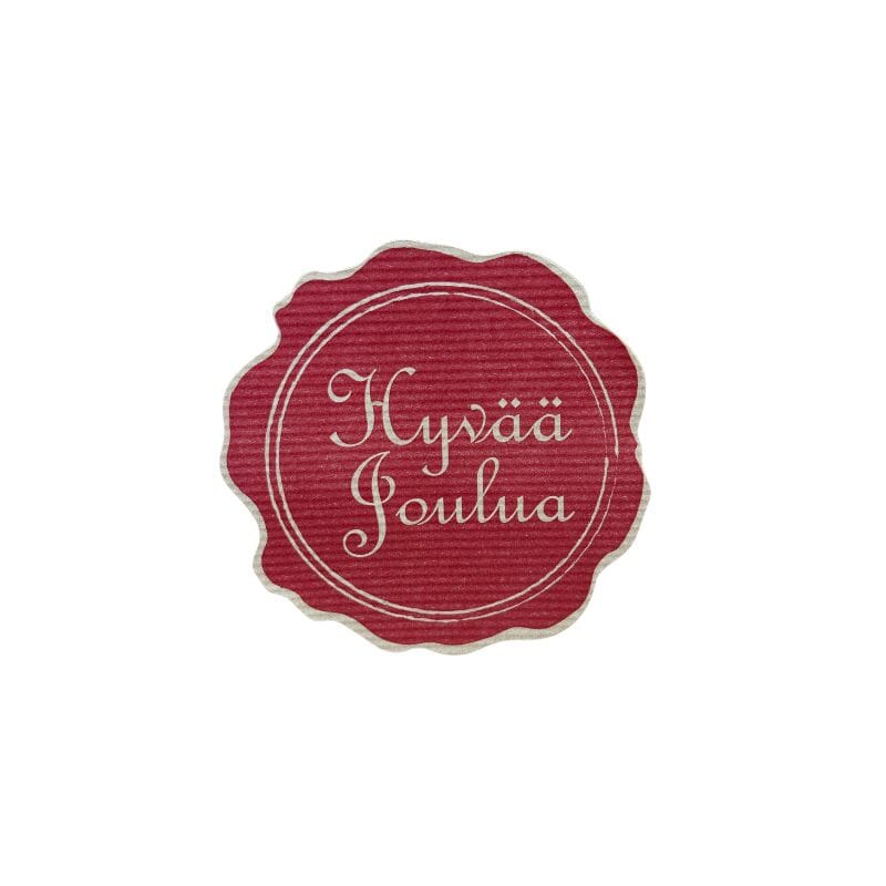 Pieni pyöreä Sinetti-tarra, jossa punaisella pohjalla hillityn kultaisella teksti "Hyvää joulua" ja kaksi rengasta sen ympärillä.