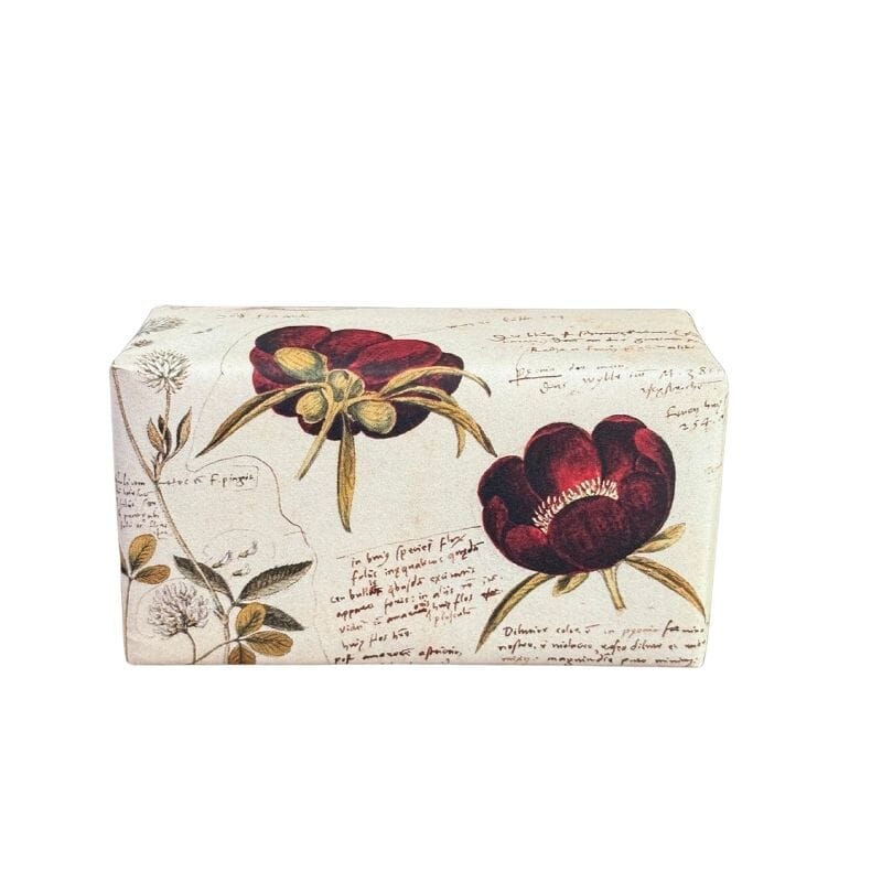 Sköna Ting Ruusu l Palasaippua 200g, jonka kauniissa paperikääreessä valkoisella pohjalla punaisia yksinkertaisia ruusuja ja valkoisia apiloita sekä koristeellista kirjoitusta.