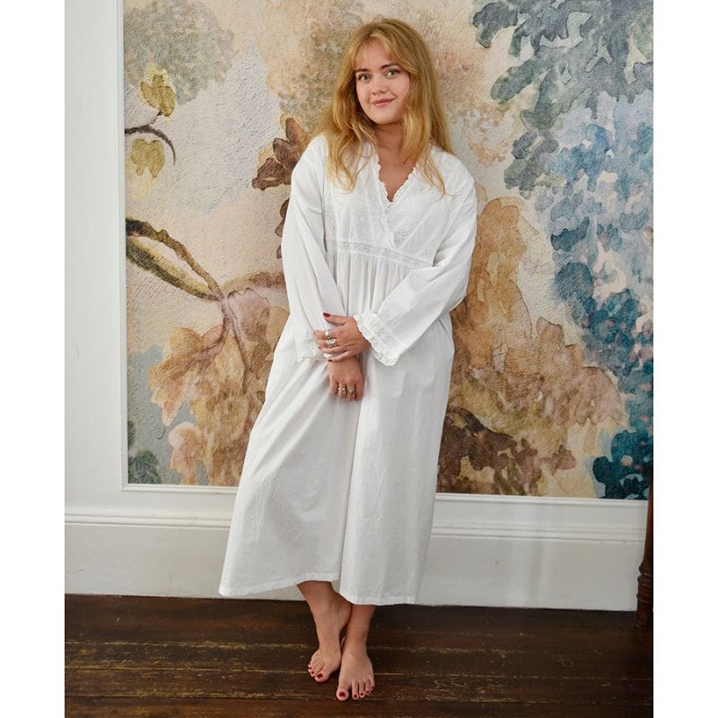 Tabitha-mallinen Powell Craftin naisten pitkähihainen puuvillainen yöpaita ruskea- ja petroolisävyiden seinän edessä seisovan vaaleahiuksisen, hymyilevän naisen yllä.