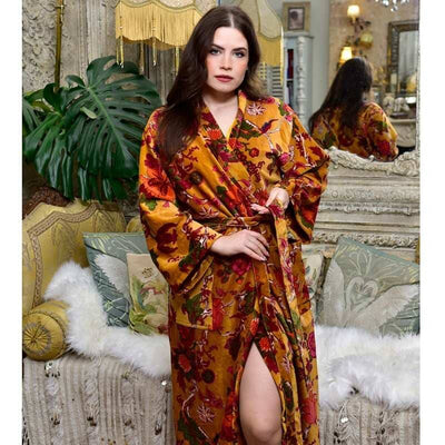 Powel Craft Velvet Mustard Floral naisten puuvillaveluurinen kimono-aamutakki tummahiuksisen, antiikkisen sohvan edessä seisovan, naisen yllä.