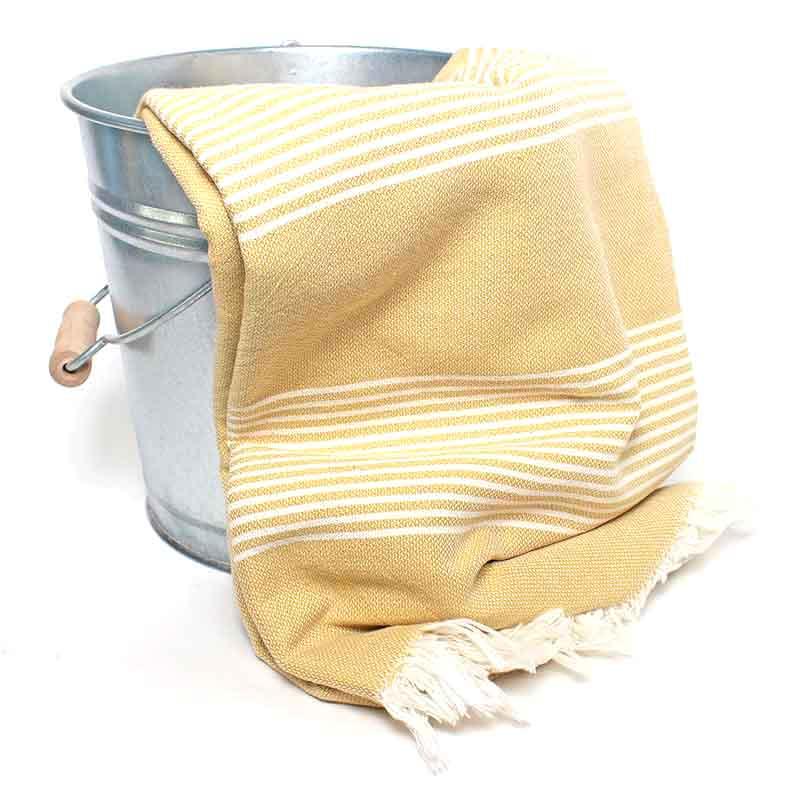 Saunatonttu by Kaurilan saunan Alman Hamam-pyyhe sävyssä Sinappi, jossa sinapinkeltaisella pohjalla kapeita valkeita raitoja ja päissä valkeat kevyet hapsut.