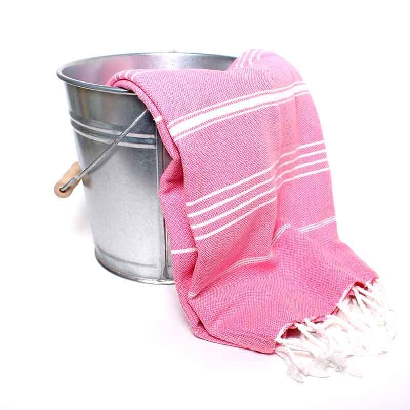 Saunatonttu by Kaurilan saunan Elsan Hamam-pyyheliina sävyssä Fuksia, jossa fuksianpinkillä pohjalla harvassa valkoisia raitoja ja päissä valkoiset kierrehapsut.