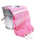 Saunatonttu by Kaurilan saunan Elsan Hamam-pyyheliina sävyssä Fuksia, jossa fuksianpinkillä pohjalla harvassa valkoisia raitoja ja päissä valkoiset kierrehapsut.