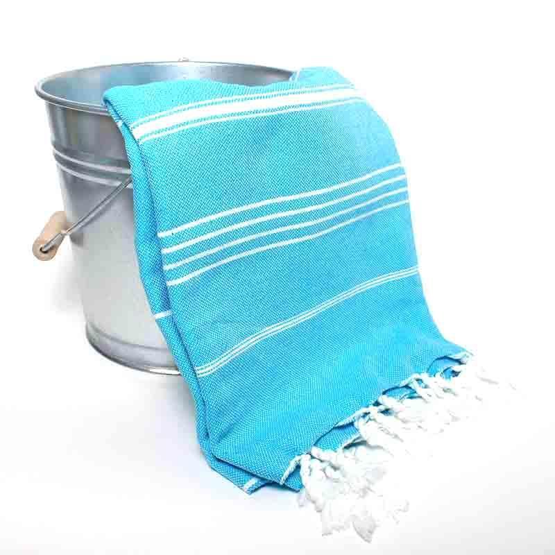 Saunatonttu by Kaurilan saunan Elsan Hamam-pyyheliina sävyssä Turkoosi, jossa turkoosinsinisellä pohjalla harvassa valkoisia raitoja ja päissä valkoiset kierrehapsut.