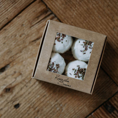 Ikkunallisessa pahvirasiassa näkyy neljä Kaurilan Saunan valkoista kanervan kuivatuilla kukilla koristeltua greippi jalkakylpytablettia.