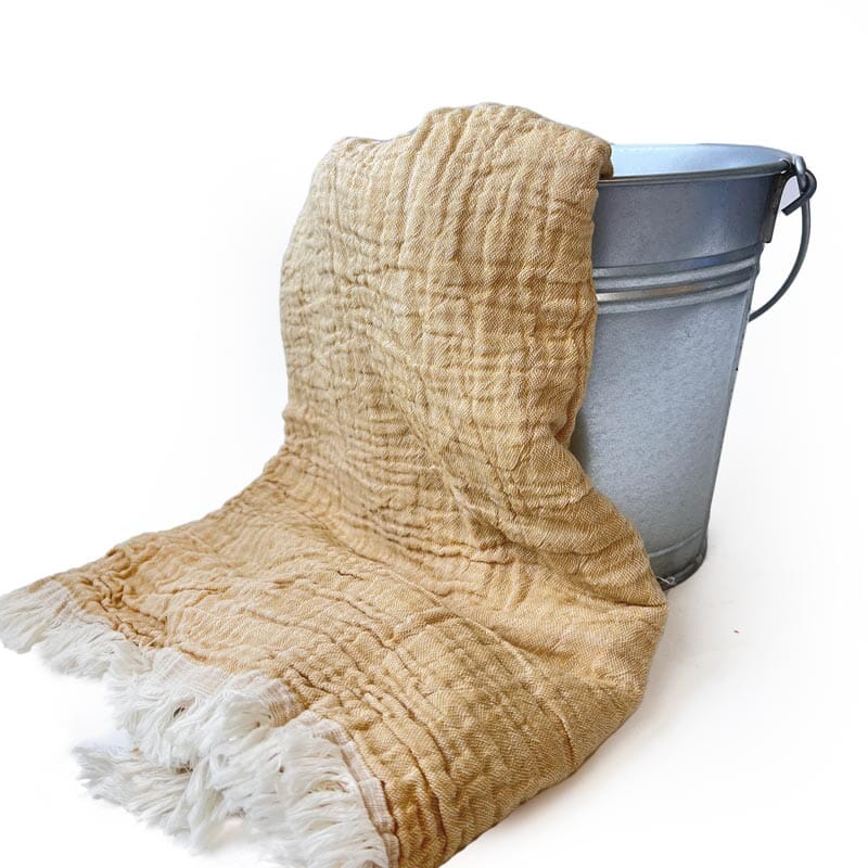 Saunatonttu by Kaurilan saunan Helenan Hamam-pyyhe sävyssä Okra, jossa pehmeästi ryppyinen okrankeltainen pinta ja päissä vaaleat kevyehköt hapsut.