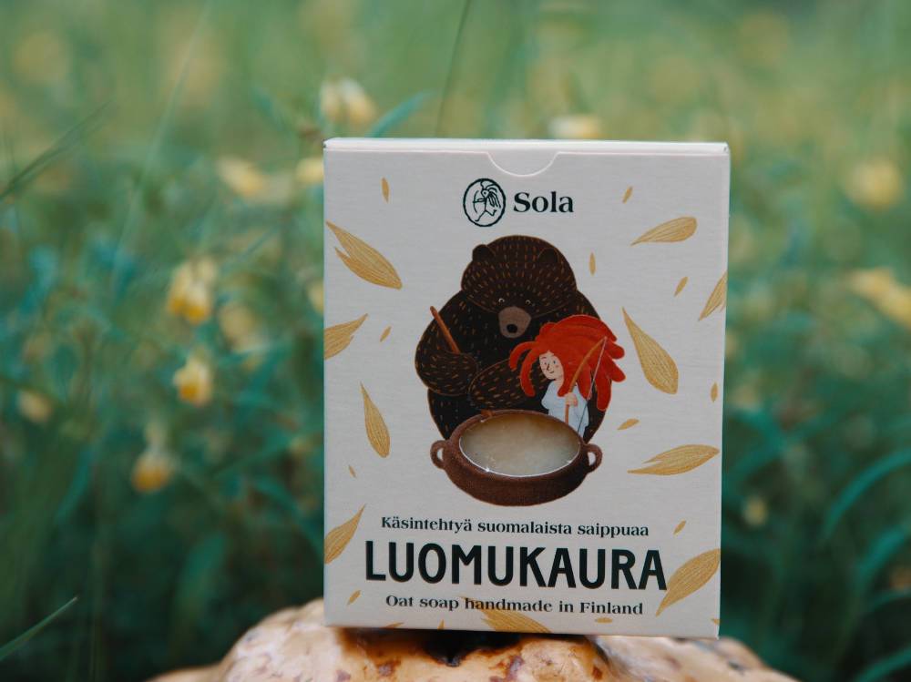 Solan Luomukaura-saippua pahkan päällä, kukkaniityn reunalla.
