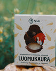 Solan Luomukaura-saippua pahkan päällä, kukkaniityn reunalla.