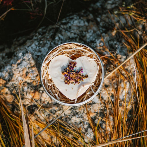 Kaurilan saunan sydämenmuotoinen mustaherukka-palashampoo metallirasiassaan luonnonkiven päällä ilta-auringossa.