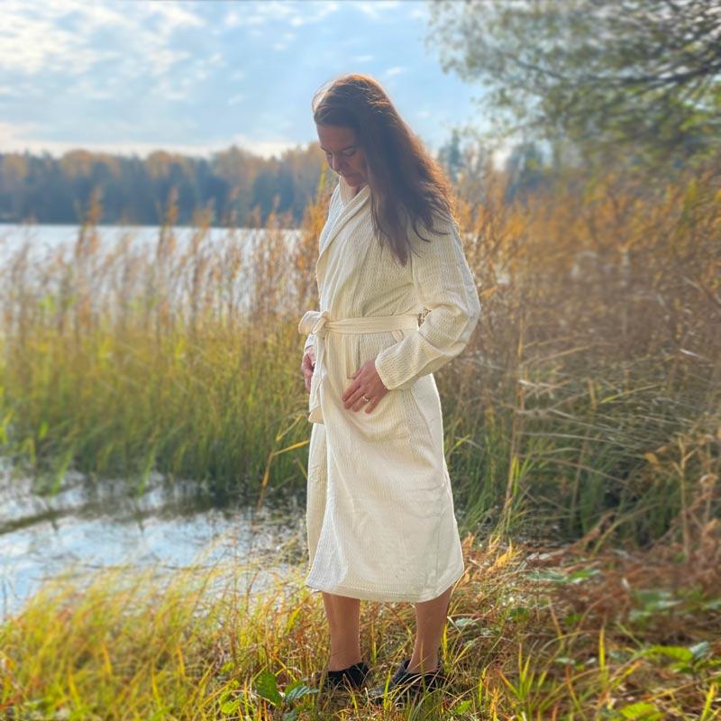 Saunatonttu by Kaurilan saunan Terhin bambu-kylpytakki rantakaislikossa kahlailevan naisen yllä.