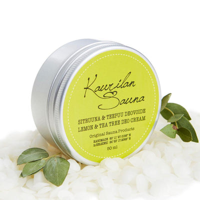 Kaurilan saunan Sitruuna & teepuu -deovoide kierrekorkillisessa metallipurkissa, jossa keltavihreä etiketti. Edustalla lehtiä ja mehiläisvaharakeita.